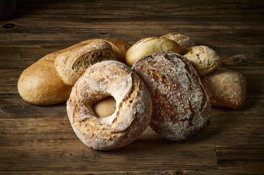 Fırındaki ahşap masa üzerinde çeşitli taze pişmiş ekmek çeşitleri