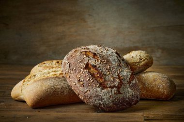 Fırındaki ahşap masa üzerinde çeşitli taze pişmiş ekmek çeşitleri