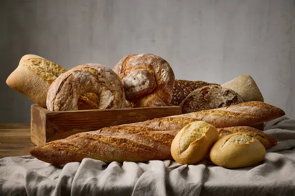 Fırındaki ahşap masa üzerinde çeşitli taze pişmiş ekmek çeşitleri