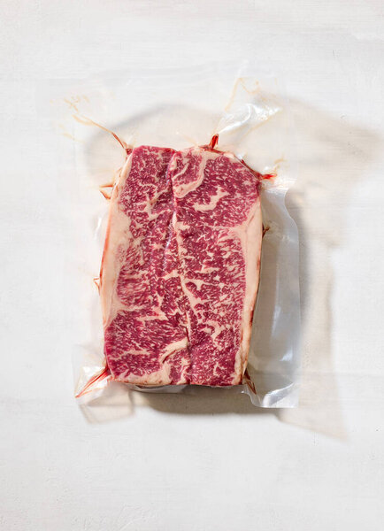 fresh raw Australian Wagyu steak on light sunny kitchen table surface, top view