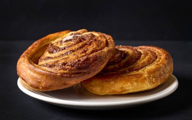 Siyah zemin üzerinde taze pişmiş tatlı tarçın ruloları