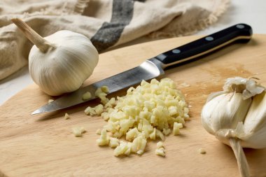 Taze çiğ sarımsak ve bıçak mutfak masasında tahta kesme tahtasının üzerinde. Fransız soğan çorbası yapma süreci, yakın plan yemek, sağlıklı yemek için sarımsak kesme.