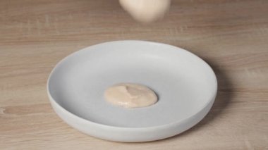 Fasulye sarımsaklı püre, sağlıklı bir vegan yemeği için ev mutfağında kaşıkla beyaz bir tabağa konur. Yiyeceklere yakın çekim