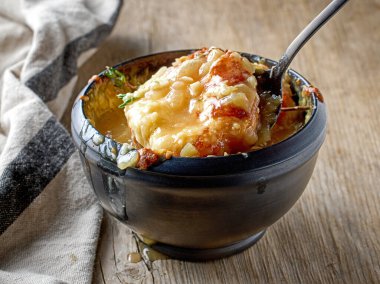 Peynirli tost ile bir kase Fransız soğan çorbası ve ahşap kırsal mutfak masasında kekik.