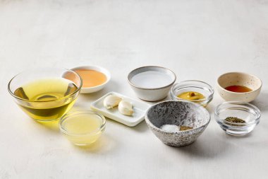 Beyaz masa arkasında çeşitli salata sosu malzemeleri var.