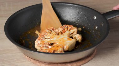 Mutfakta sağlıklı bir vejetaryen yemeği için eritilmiş tereyağlı tavada karnabahar bifteği kızartıyorum.