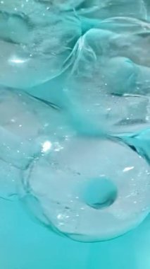 Soğuk mavi kokteyl içeceğindeki buz küplerinin yavaş hareket etmesi. içecek yakın çekim, makro