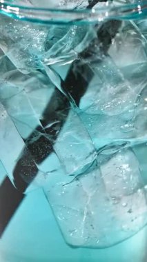 Buzlu taze mavi içecekten yapılmış kokteyl bardağı. El cam makronun içine saman koydu