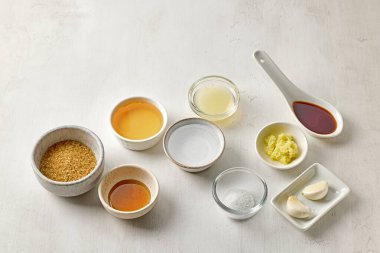 Beyaz masa arkasında çeşitli salata sosu malzemeleri var.