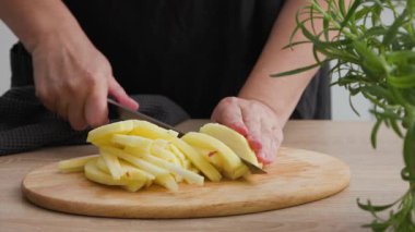 Aşçı, sağlıklı vejetaryen salatası yapmak için mutfak mutfağında ahşap kesim tahtasında taze çiğ elma kesti. 