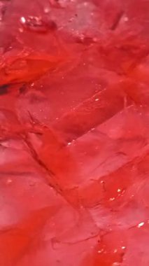 Soğuk kırmızı kokteyl içeceğindeki buz küplerinin yavaş hareket etmesi. içecek yakın çekim, makro