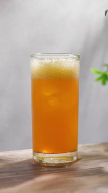 Taze portakal suyu bardakta güneşli ahşap mutfak masasında ve gri arka planda, ağır çekim