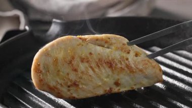 Aşçı, sağlıklı bir yemek hazırlamak için tavuklu fileto pişiriyor. Yemekler yakınlaştırılsın.