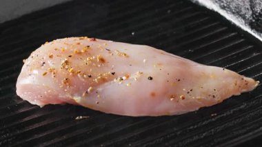 Taze çiğ tavuk fileto eti ve sıcak ızgarada pişirilen baharatlar. Yemek yakın çekim, uzaklaşma.