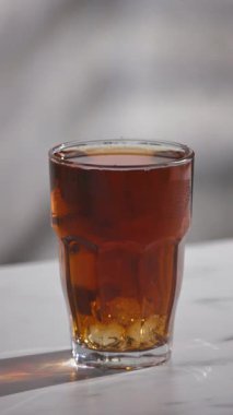 Buz küpü bir bardak buzlu çaya düşer ve yavaş çekimde gri mutfak masasına su sıçratır.