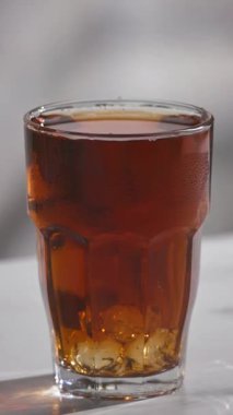 Buz küpü bir bardak buzlu çaya düşer ve yavaş çekimde gri mutfak masasına su sıçratır.