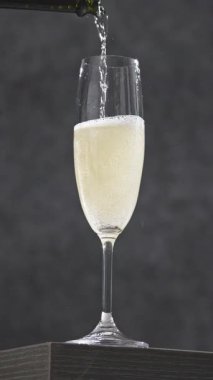 Gri arkaplandan dökülen taze şampanya, yakın plan.