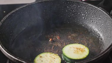 Aşçı taze kabak dilimleri ve sıcak yağda baharat koydu. Lezzetli sağlıklı yemek ve yakın yemek hazırlamak için.