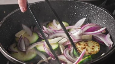 Patates kızartması dilimlenmiş taze kırmızı soğan ve baharatlı kabak parçaları ve sıcak yağda sarımsak. Lezzetli ve sağlıklı bir yemek hazırlamak için.