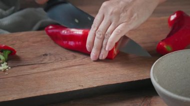 Aşçı ahşap mutfak tahtasına taze kırmızı biber koydu ve tohumları temizledi. Yemek yakın çekim, gazpacho çorbası yapma süreci.