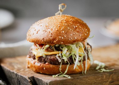Taze lezzetli burger, ahşap kırsal kesim tahtasında, restoran masasında.