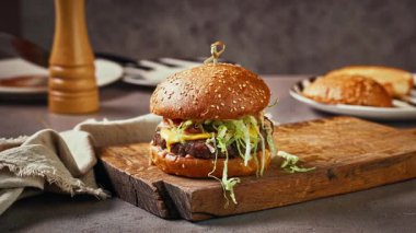 Köy mutfağındaki ahşap kesme tahtasındaki taze lezzetli burger, yakınlaştır.