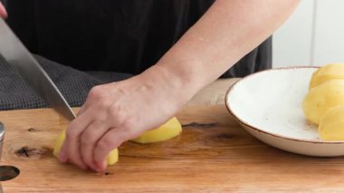 Aşçı, saglikli patates püresi yapmak icin saglikli bir mutfakta ahşap kesim tahtasinda taze çiğ patates, yiyecek kapisi. 