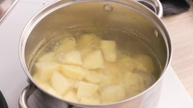 Aşçı patatesleri patates püresi için bir tencere suda haşlıyor ve donutu bıçakla kontrol ediyor..