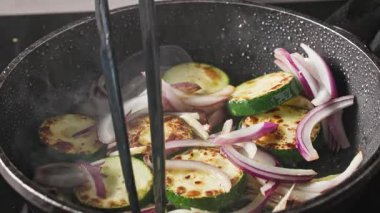 Patates kızartması dilimlenmiş taze kırmızı soğan ve baharatlı kabak parçaları ve sıcak yağda sarımsak. Lezzetli ve sağlıklı bir yemek hazırlamak için.