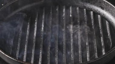 Aşçı ızgarada domuz pirzolası pişiriyor.