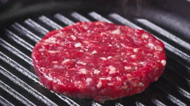 Pişirmek için sıcak ızgara tavada taze çiğ sığır etli burger eti, yakın çekim.