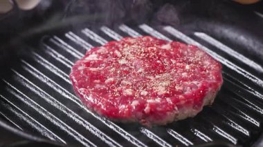 Sıcak ızgarada biberli taze kırmızı kıymalı hamburger eti pişirir, pişirir, diğer tarafa çevirir, yemekleri yakınlaştırır.