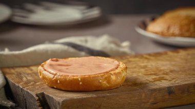 Aşçı ızgara hamburger eti ve erimiş peynirli ekmeği ahşap kesme tahtasına, yiyecek yakın plan.