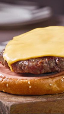 Şef, ev mutfağında lezzetli bir biftek burgeri hazırlıyor, ahşap bir tahtanın üzerinde, yemek yakın plan.