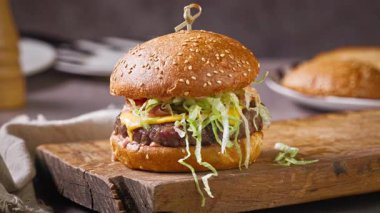 Şef, ev mutfağında lezzetli bir biftek burgeri hazırlıyor, ahşap bir tahtanın üzerinde, yemek yakın plan.