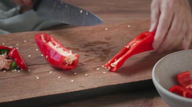 Aşçı ahşap mutfak tahtasına taze kırmızı biber koydu ve tohumları temizledi. Yemek yakın çekim, gazpacho çorbası yapma süreci.