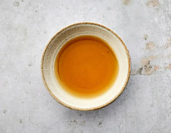 Gri arka planda bir kase susam yağı, üst manzara.