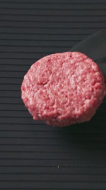 Şef pişirmek için sıcak elektrikli ızgaraya taze çiğ et köftesi, yakın plan yemek koyar.