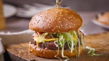 Köy mutfağındaki ahşap kesme tahtasındaki taze lezzetli burger, zoom. 