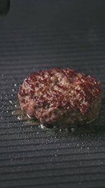 Aşçı sıcak elektrikli ızgara tavadan ızgara sulu sığır burger etini kaldırır