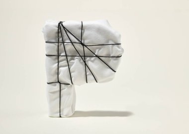 beyaz kumaşla sarılmış P harfi, bej arkaplanda siyah dizgi ile