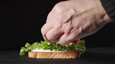 Bir aşçı, kulüp sandviçi yapmak için taze kızarmış ekmeğin üzerine domates dilimleri koydu. Sağlıklı yemek yapma süreci