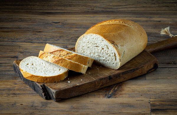 freshly baked sliced bread on rustic wooden kitchen table in bakery 