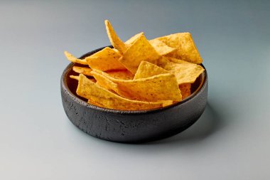 Gri arka planda izole edilmiş bir kase tortilla soyulmuş cips.