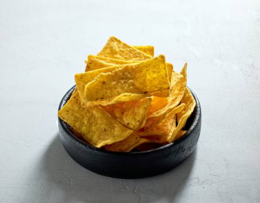 Gri masa arkasında bir kase tortilla cips.