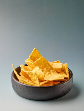 Gri arka planda izole edilmiş bir kase tortilla soyulmuş cips.