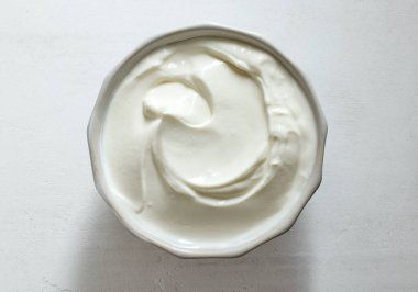 Beyaz mutfak masasına bir kase ekşi kremalı yoğurt sosu.
