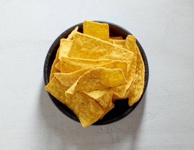 Bir kase tortilla cips beyaz mutfak masasında, üst manzara