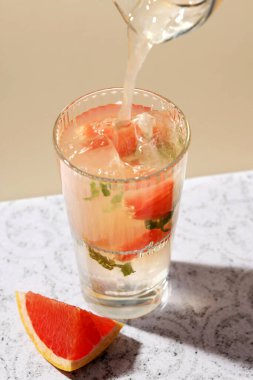 Gri masa arkasında bir bardak greyfurt kokteyli.