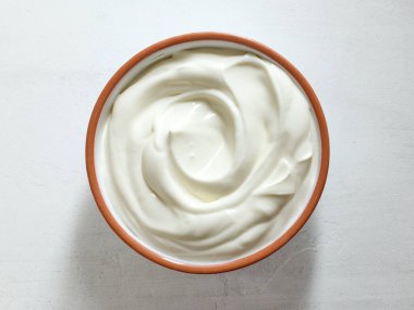 Beyaz mutfak masasına bir kase ekşi kremalı yoğurt sosu.